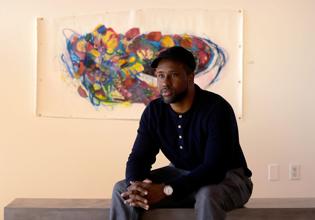 Askia Bilal sits in front of his piece
